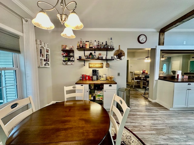 dining room with ceiling fan with notable chandelier, light hardwood / wood-style floors, and ornamental molding