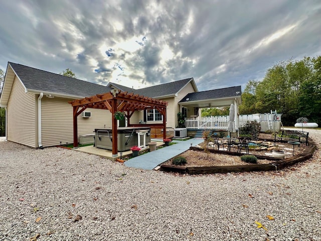 rear view of house featuring a pergola, a hot tub, central AC unit, and a patio area