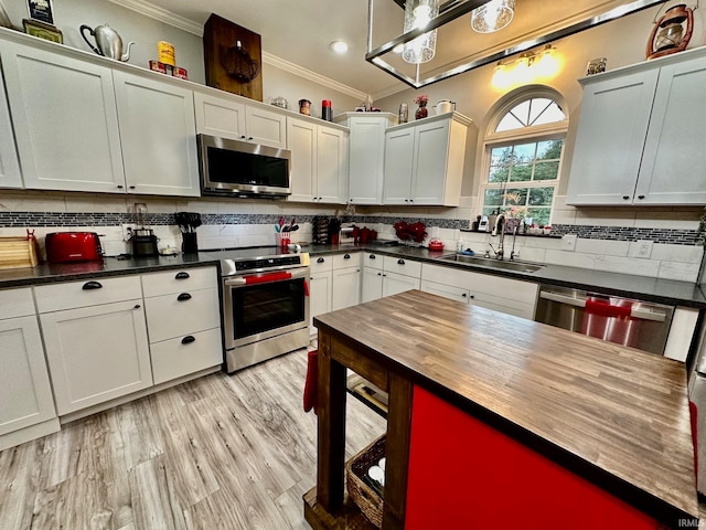 kitchen with ornamental molding, appliances with stainless steel finishes, tasteful backsplash, and sink