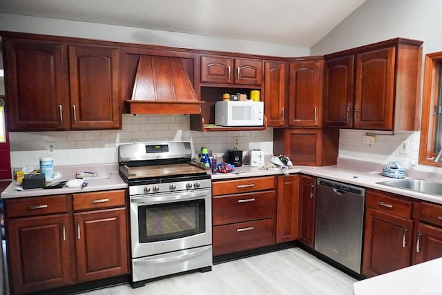 kitchen featuring light hardwood / wood-style flooring, custom exhaust hood, appliances with stainless steel finishes, and decorative backsplash