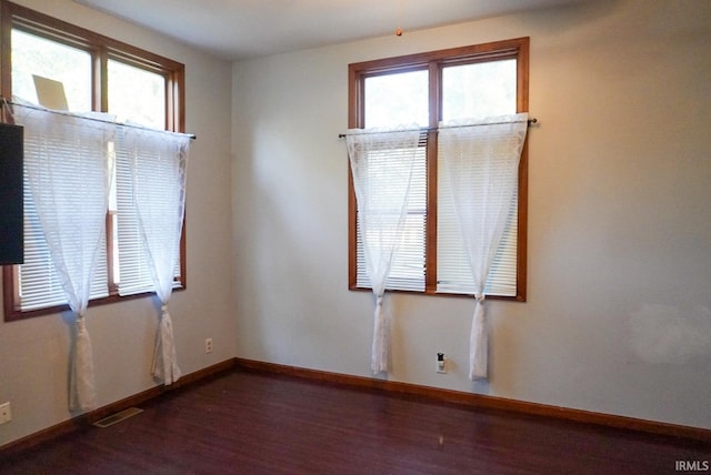 empty room featuring plenty of natural light and dark hardwood / wood-style flooring