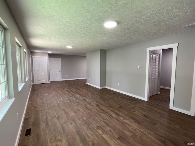 empty room featuring a textured ceiling and dark wood-type flooring