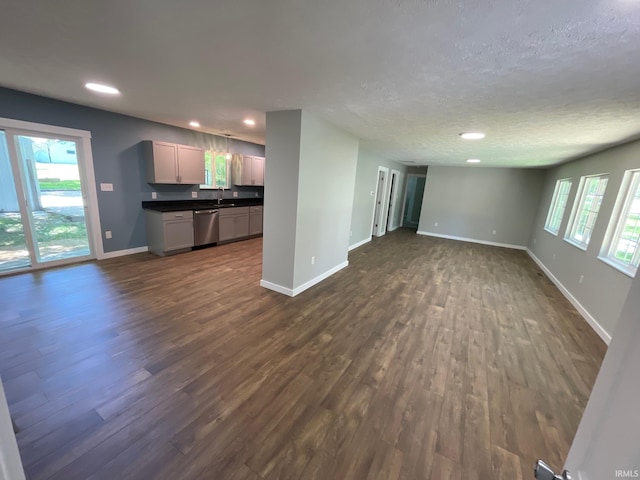 unfurnished living room with a textured ceiling, dark wood-type flooring, and sink