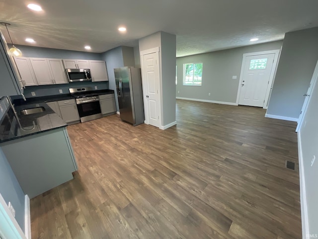 kitchen with pendant lighting, a textured ceiling, sink, stainless steel appliances, and dark hardwood / wood-style flooring