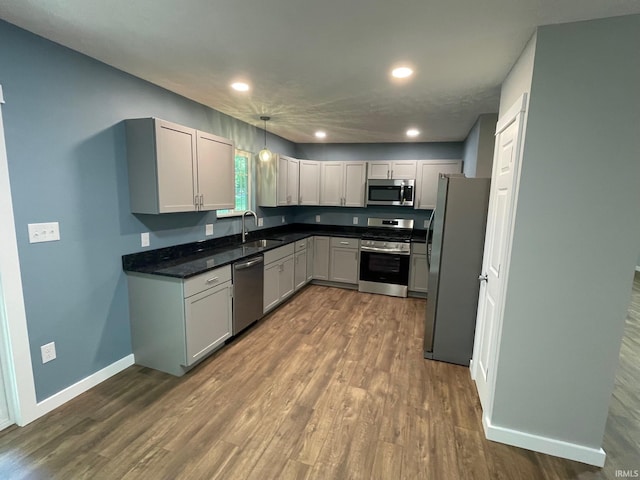 kitchen featuring pendant lighting, sink, gray cabinetry, appliances with stainless steel finishes, and dark hardwood / wood-style flooring