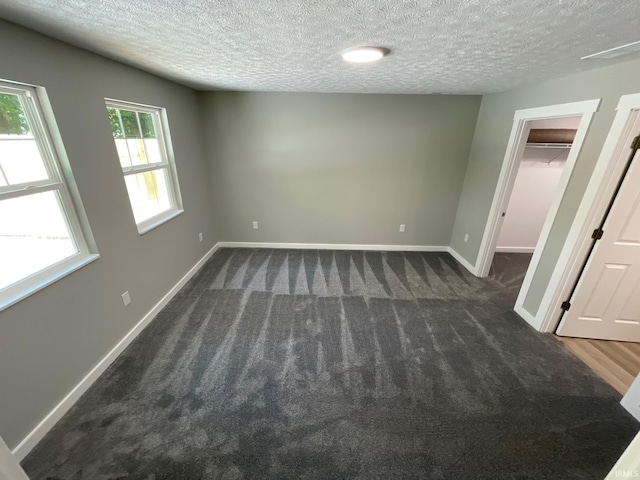 carpeted empty room with a textured ceiling