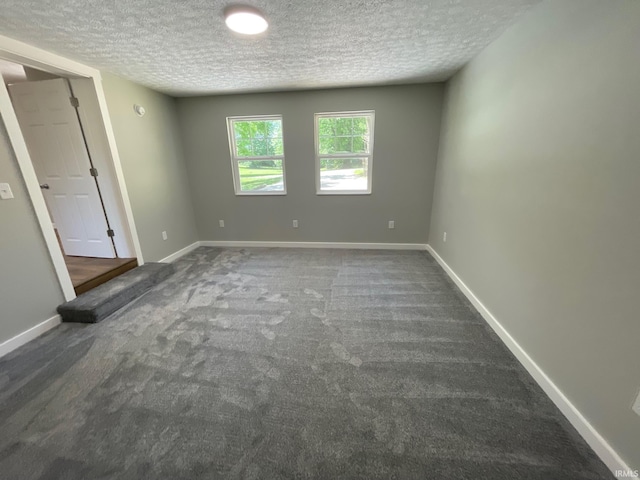 carpeted empty room featuring a textured ceiling