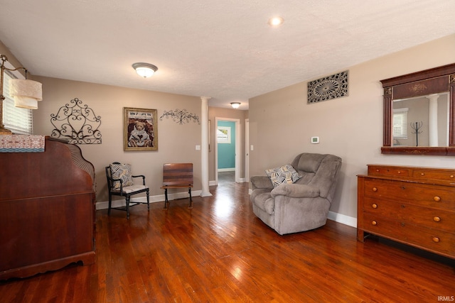 living area with a textured ceiling, decorative columns, dark wood-type flooring, and plenty of natural light