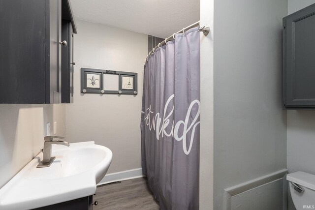 bathroom featuring curtained shower, vanity, a textured ceiling, toilet, and hardwood / wood-style floors