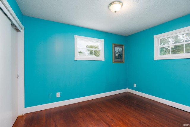 unfurnished room featuring wood-type flooring and a textured ceiling