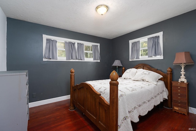 bedroom featuring multiple windows, a textured ceiling, and dark hardwood / wood-style flooring