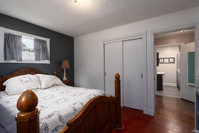 bedroom featuring a textured ceiling, dark wood-type flooring, and a closet