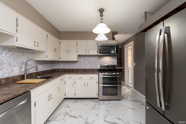 kitchen with tasteful backsplash, sink, white cabinets, appliances with stainless steel finishes, and decorative light fixtures