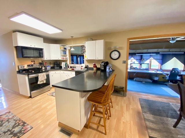 kitchen featuring stainless steel electric stove, a breakfast bar, white cabinets, kitchen peninsula, and pendant lighting