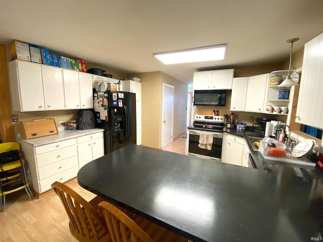 kitchen with sink, decorative light fixtures, white cabinetry, black appliances, and light hardwood / wood-style floors