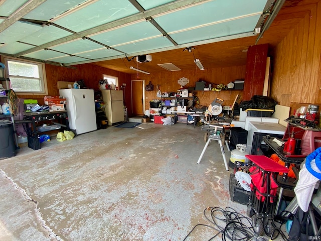 garage featuring a garage door opener, wooden walls, and white fridge