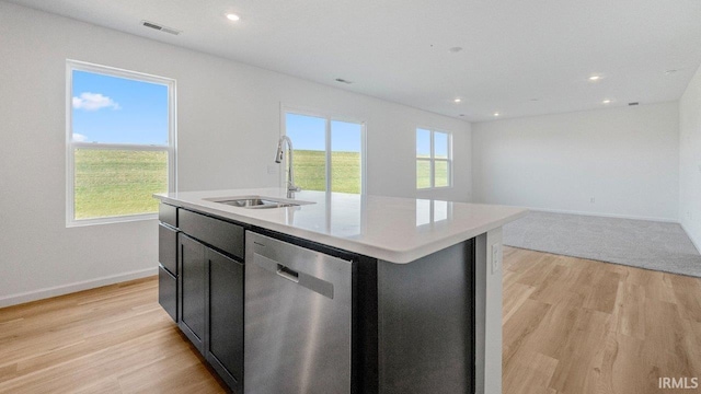 kitchen featuring dishwasher, an island with sink, light hardwood / wood-style flooring, and sink