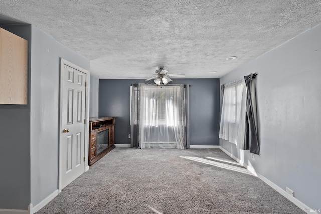 unfurnished living room with carpet, ceiling fan, and a textured ceiling