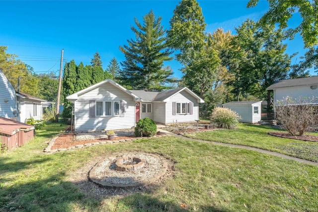 view of front of house with a storage shed, a front yard, and an outdoor fire pit