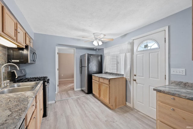 kitchen with light wood-type flooring, a textured ceiling, sink, appliances with stainless steel finishes, and ceiling fan