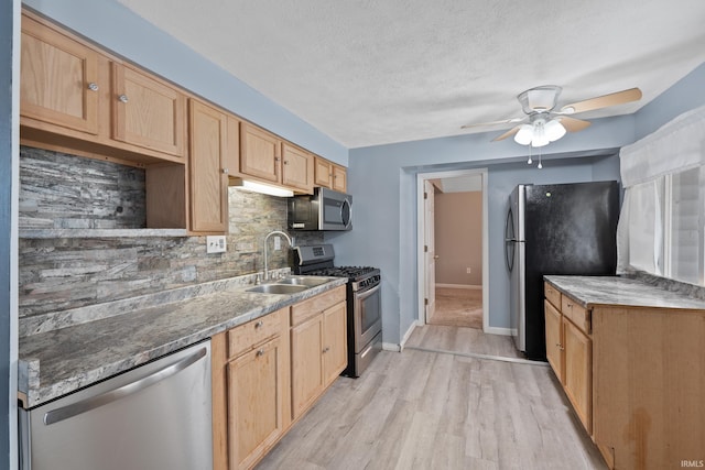 kitchen featuring a textured ceiling, light hardwood / wood-style floors, tasteful backsplash, sink, and appliances with stainless steel finishes