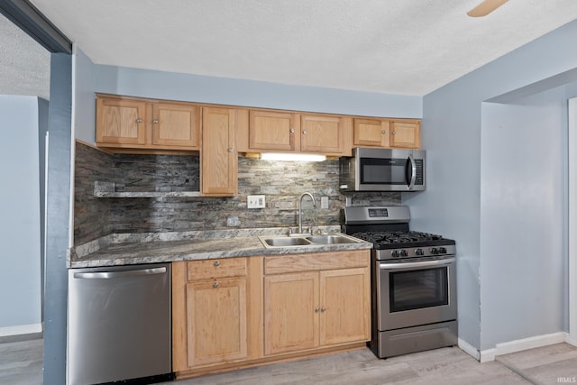 kitchen featuring appliances with stainless steel finishes, light wood-type flooring, sink, and tasteful backsplash