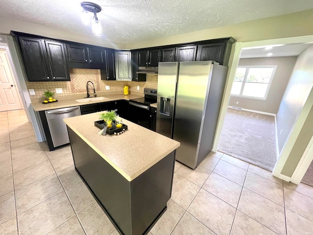 kitchen featuring light tile patterned flooring, sink, tasteful backsplash, a kitchen island, and stainless steel appliances