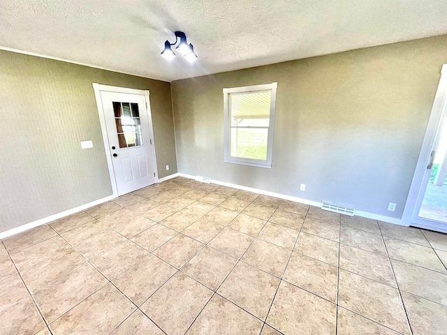 unfurnished room featuring a textured ceiling and light tile patterned flooring