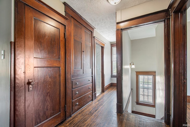 corridor featuring a textured ceiling and dark hardwood / wood-style flooring