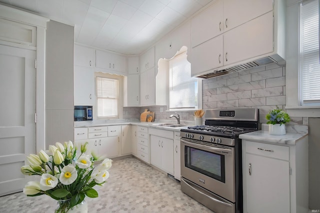 kitchen with plenty of natural light, white cabinetry, and gas range