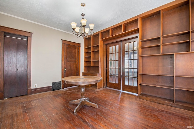 interior space featuring french doors, a notable chandelier, dark wood-type flooring, and crown molding