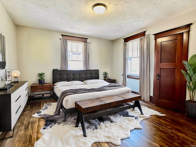 bedroom with a textured ceiling and dark hardwood / wood-style flooring