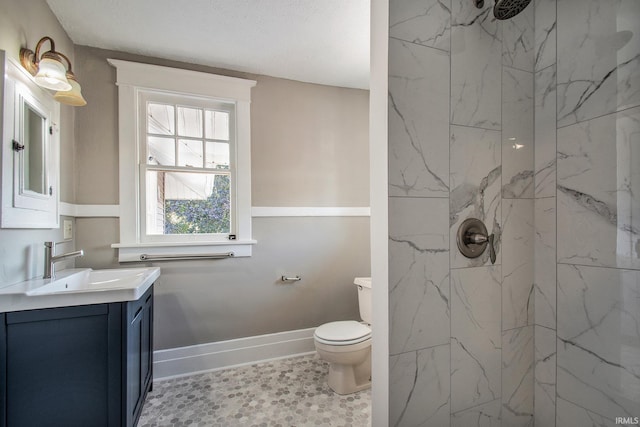 bathroom with vanity, a textured ceiling, a tile shower, toilet, and tile patterned floors