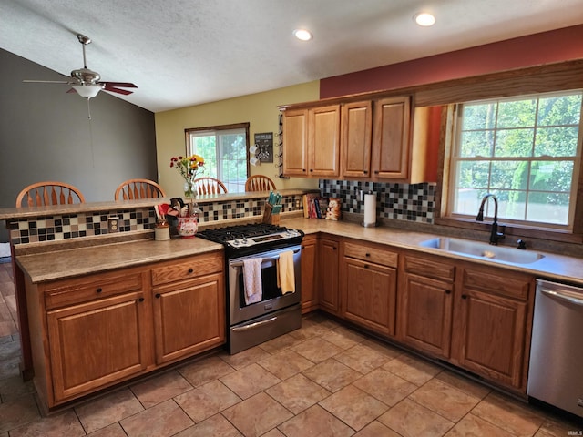 kitchen featuring sink, kitchen peninsula, a textured ceiling, stainless steel appliances, and decorative backsplash