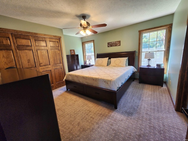 carpeted bedroom with multiple windows, a textured ceiling, ceiling fan, and a closet