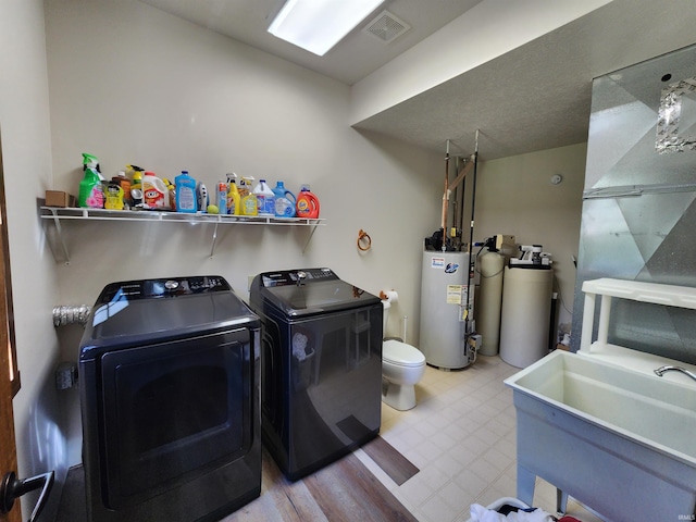 laundry room featuring washer and clothes dryer, gas water heater, light hardwood / wood-style flooring, and sink