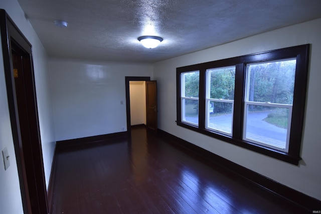 empty room featuring a textured ceiling and dark wood-type flooring