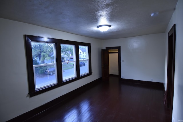 unfurnished room featuring a textured ceiling and dark wood-type flooring