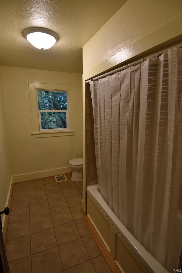 bathroom with shower / bathtub combination with curtain, tile patterned flooring, a textured ceiling, and toilet