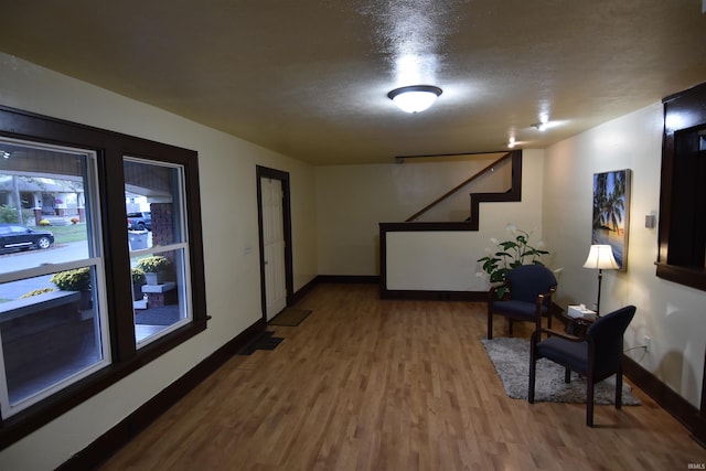 corridor with a textured ceiling and hardwood / wood-style flooring