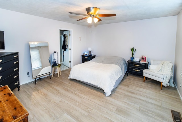 bedroom with a closet, a spacious closet, light wood-type flooring, and ceiling fan