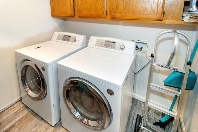 laundry area featuring cabinets, independent washer and dryer, and light hardwood / wood-style floors