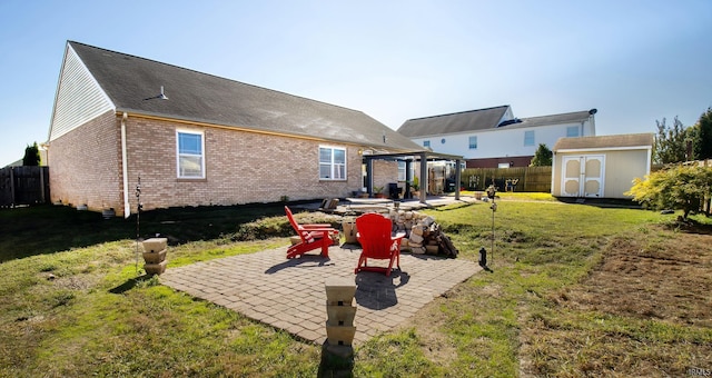 rear view of house with a patio, a shed, a fire pit, and a yard