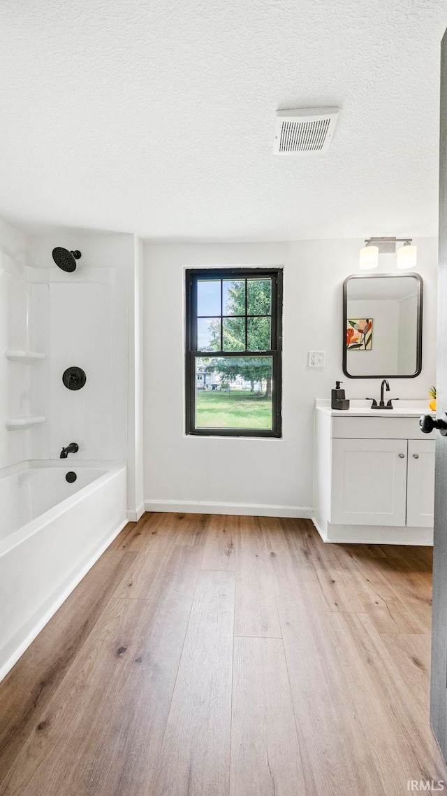 bathroom with shower / bathtub combination, hardwood / wood-style flooring, vanity, and a textured ceiling