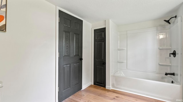 bathroom with hardwood / wood-style flooring, shower / bath combination, and a textured ceiling