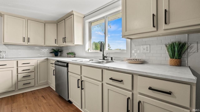 kitchen featuring light hardwood / wood-style floors, tasteful backsplash, stainless steel dishwasher, cream cabinets, and sink