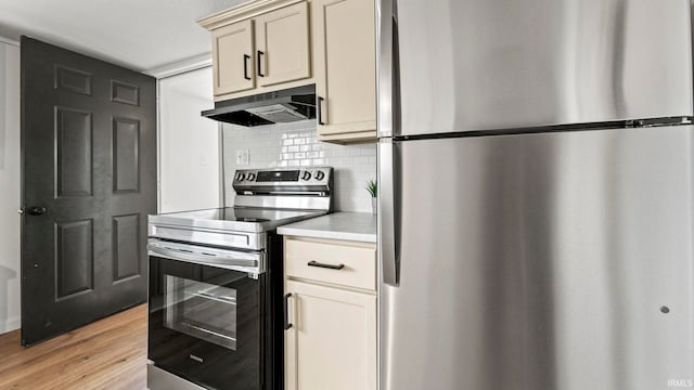 kitchen featuring cream cabinetry, backsplash, light hardwood / wood-style floors, and stainless steel appliances