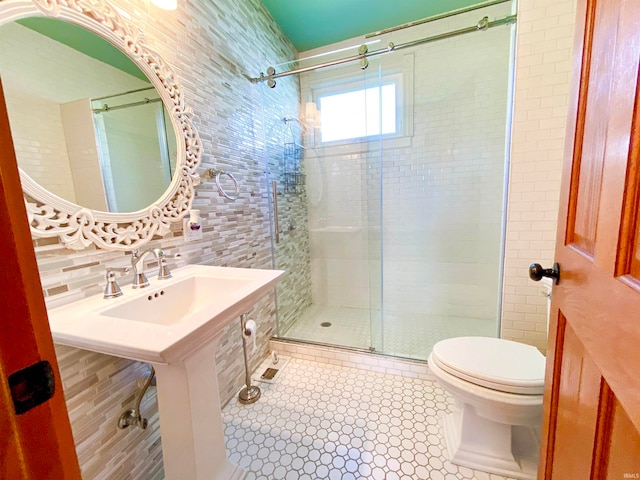 bathroom featuring sink, a shower with shower door, tile walls, toilet, and decorative backsplash