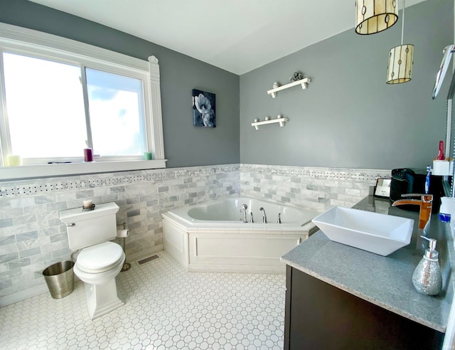 bathroom with tile walls, a tub, tile patterned floors, vanity, and toilet