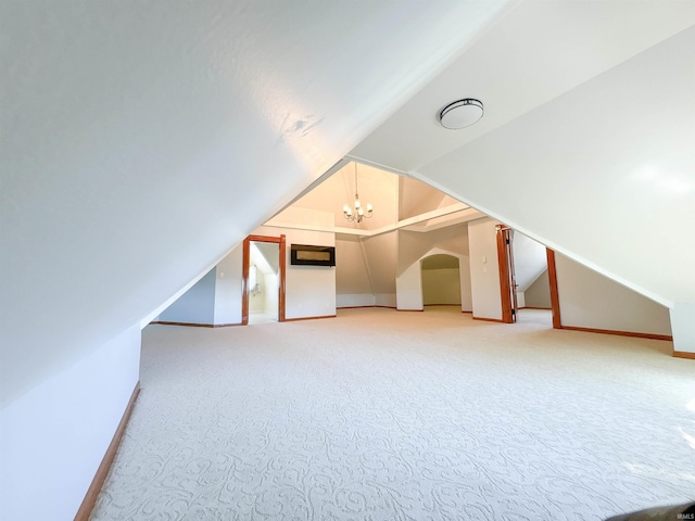 bonus room featuring a chandelier, light colored carpet, baseboards, and lofted ceiling